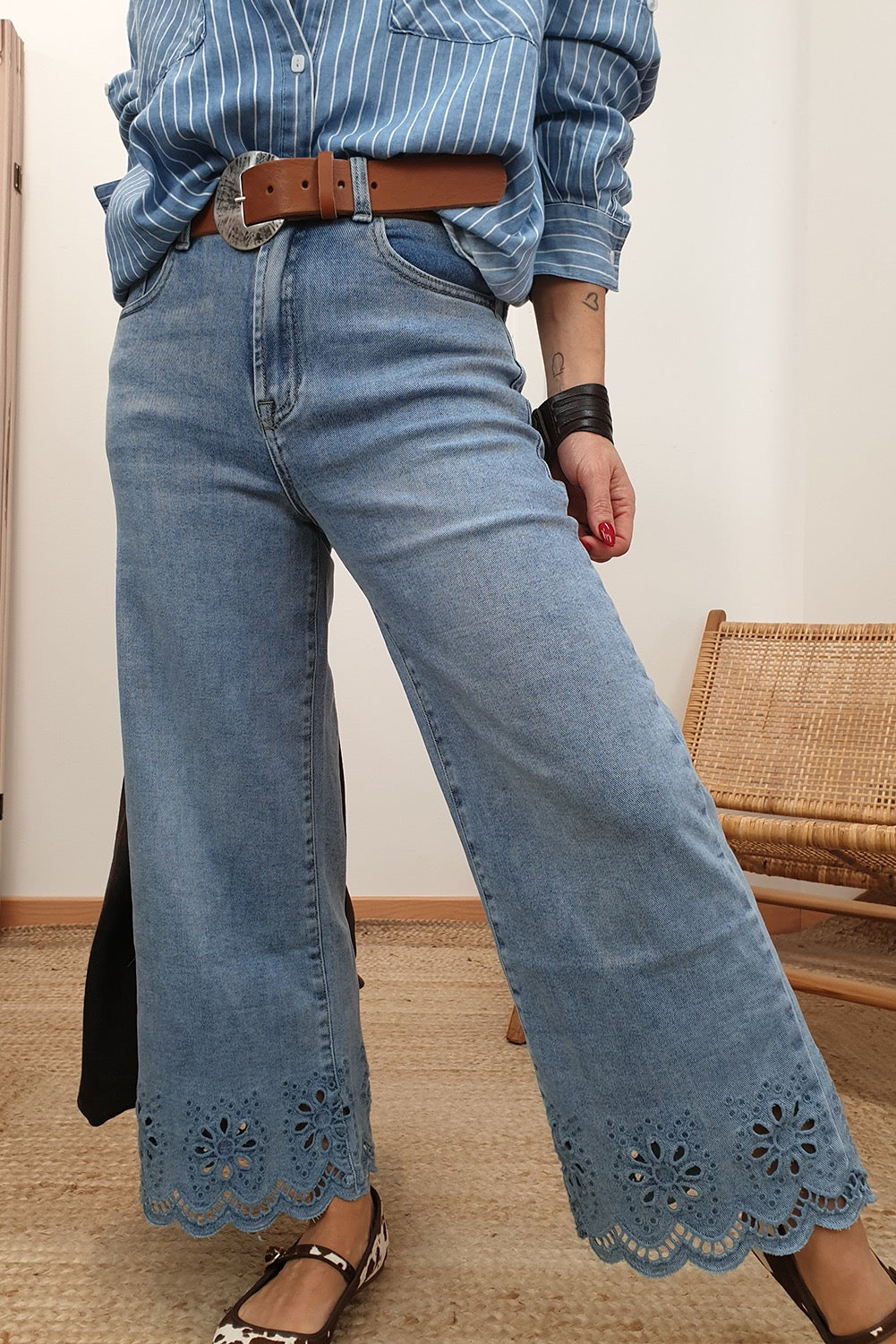 Person wearing blue jeans with lace details on a neutral background