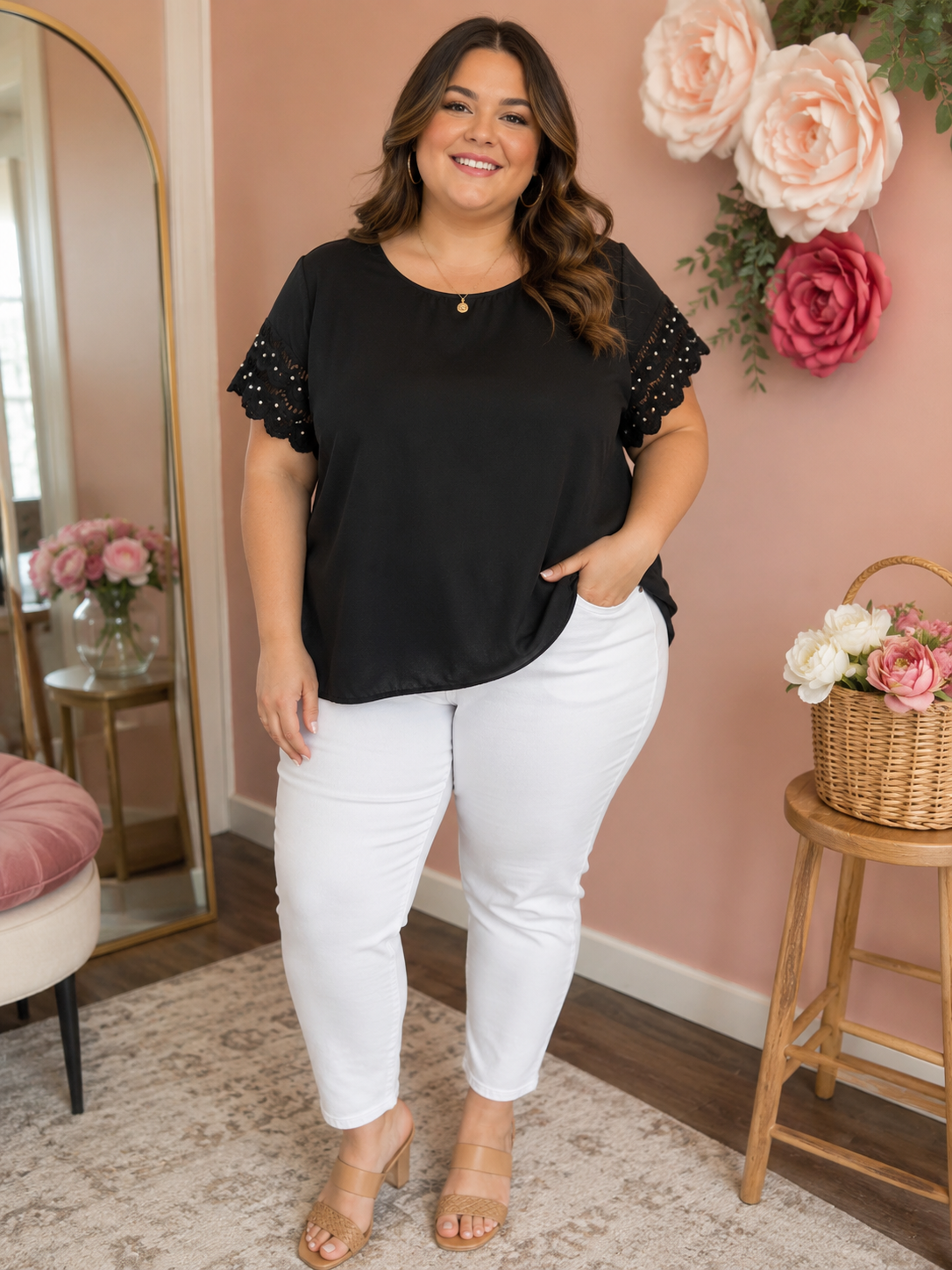 Woman wearing a black top with white pearl dots scalloped  short sleeve and white pants