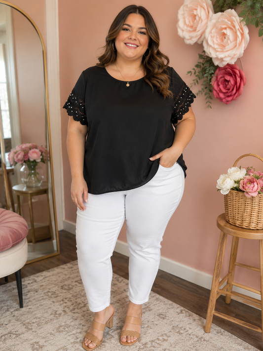 Woman wearing a black top with white pearl dots scalloped  short sleeve and white pants
