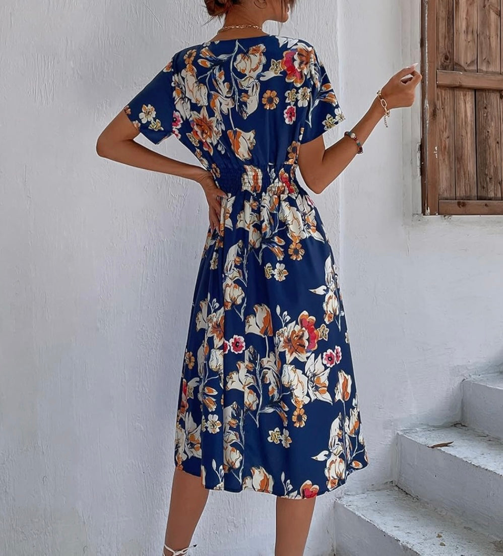Woman wearing a floral dress with a white wall and wooden door in the background