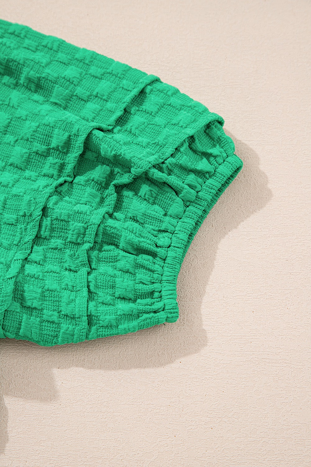Green textured fabric on a beige background