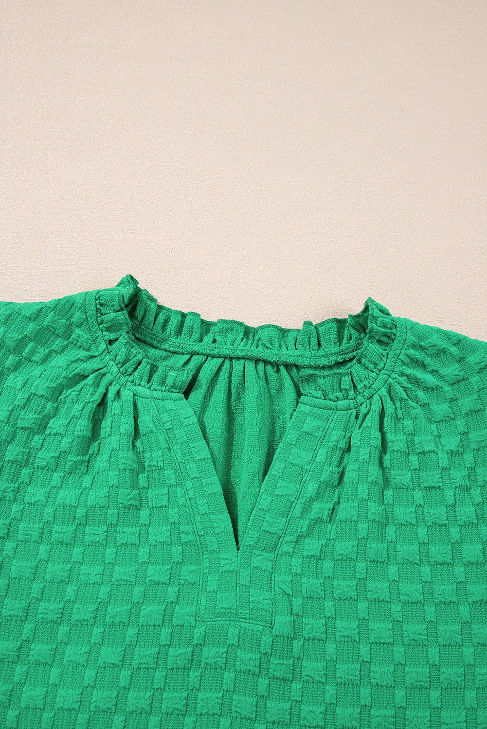 Green textured blouse with a beige background