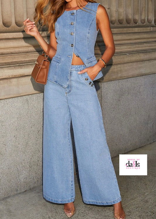 Woman wearing a denim outfit with wide-leg pants and a vest against a stone wall.