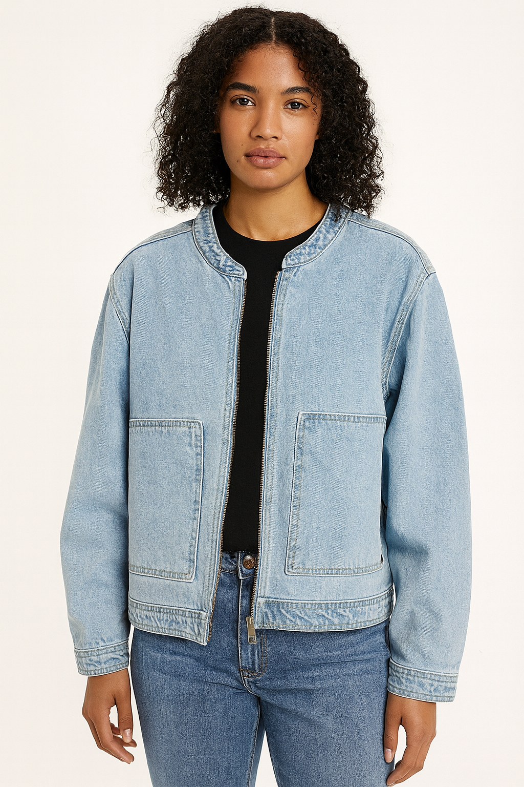 Person wearing a light blue denim jacket and jeans on a white background