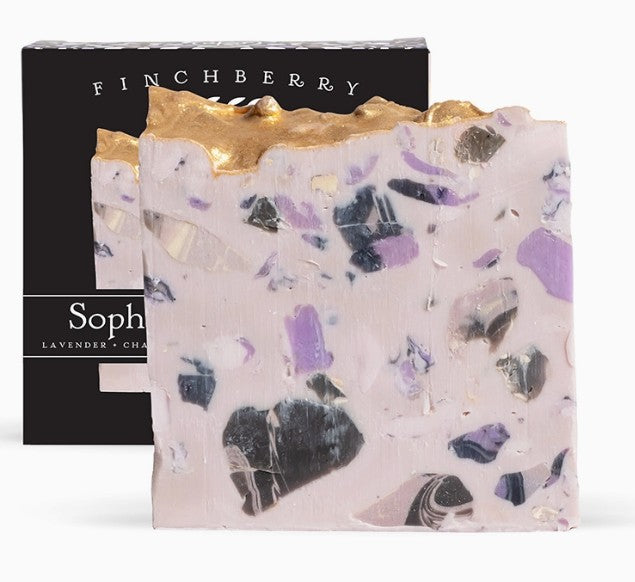 Bar of soap with gold top and visible ingredients, Finchberry packaging in the background